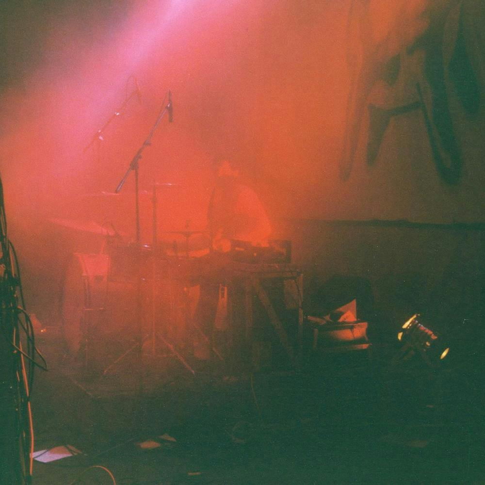 Eine vernebelte Bühne mit rotem Licht, in der Mitte sitzt jemand hinter einem Schlagzeug.