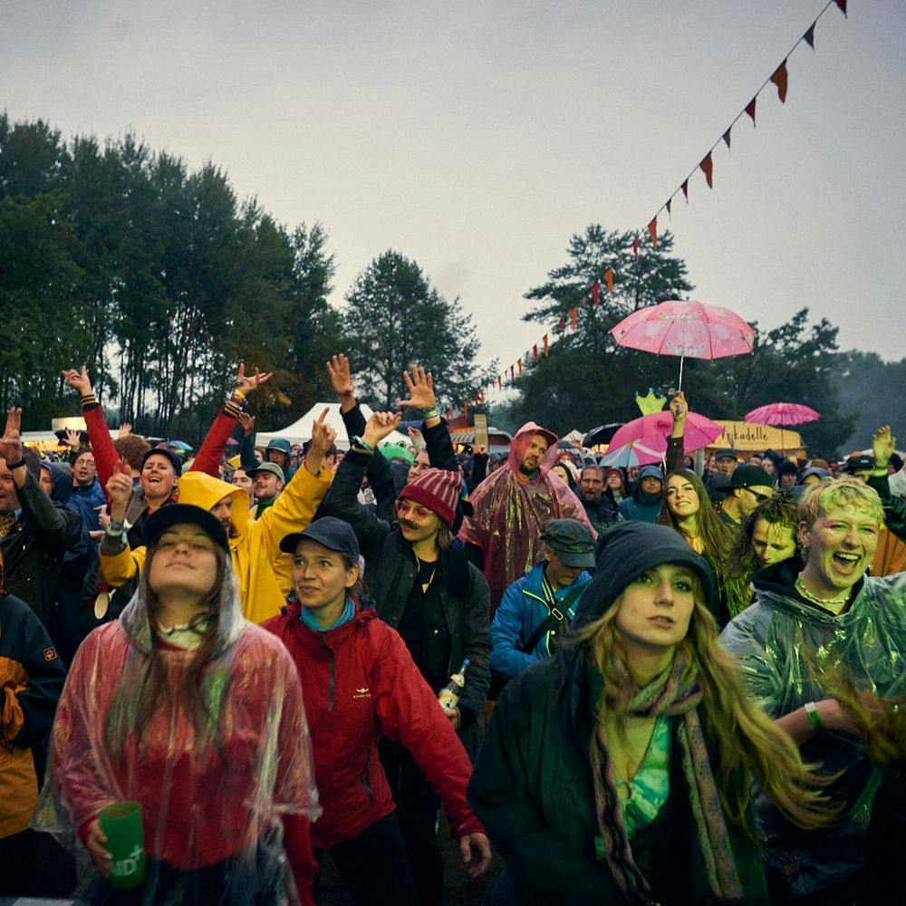 Menschen im Publikum beim Immergut mit Regencapes und Regenschirmen